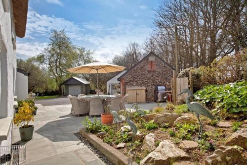 a patio with an umbrella and birds in a garden at Character barn in St Mellion in St Mellion