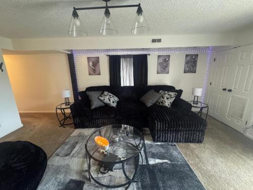 a living room with a black couch and a glass table at Elegance Escape 