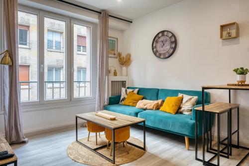 a living room with a blue couch and a clock on the wall at Frau - 2 suites avec ascenseur à côte de la Cathédrale de Rouen ! in Rouen