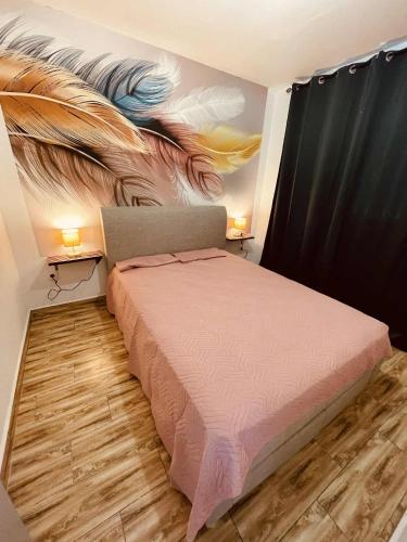 a bedroom with a bed with a painting on the wall at Le COLIBRI Sainte Anne in Saint-Benoît