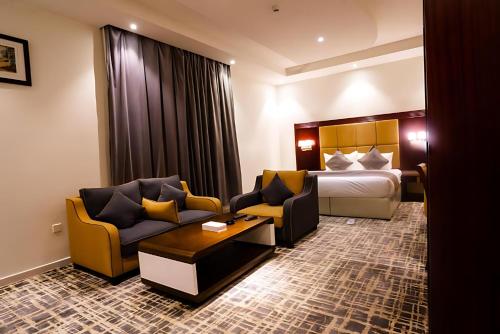 a hotel room with a bed and two chairs at الرست ان للشقق المخدومة in Jazan
