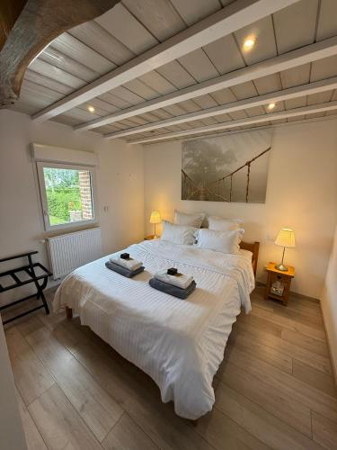 a bedroom with a large white bed with two towels on it at La grange des rosiers in Cambron