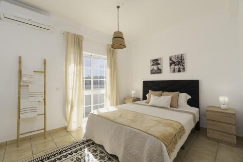 a white bedroom with a large bed and a window at Villa Menina by Ocvillas in Albufeira