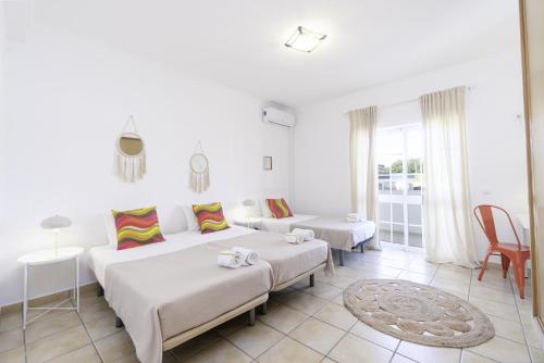 a white bedroom with two beds and a living room at Villa Menina by Ocvillas in Albufeira