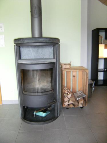 an old wood stove in a room with a tiled floor at Appartement de vacances Niederer in La Côte-aux-Fées