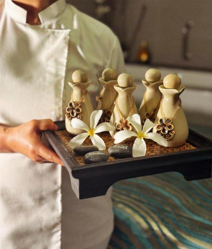 a chef holding a tray with a group of vases and flowers at Radisson Collection Muscat, Hormuz Grand in Muscat