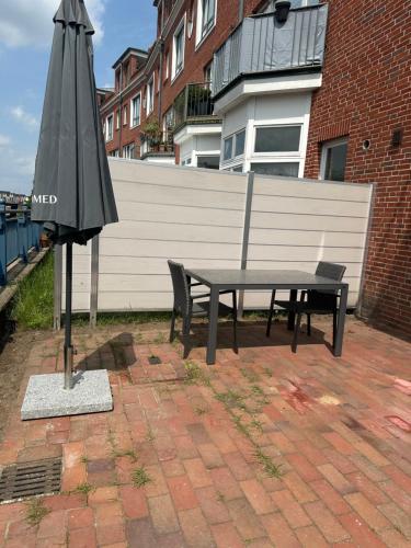 a picnic table and an umbrella on a brick patio at Terrassenwohnung City an der Kleinen Weser in Bremen