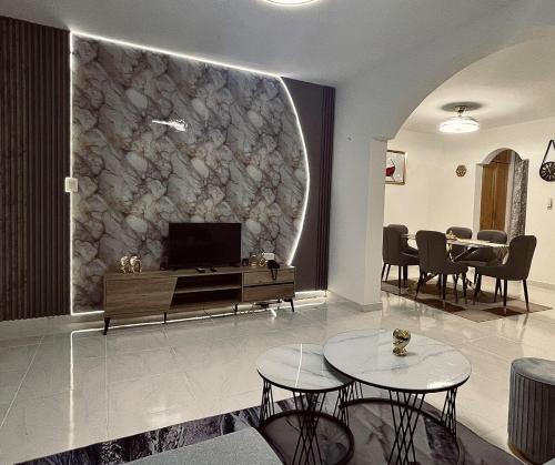 a living room with a tv and a stone wall at Modern & comfortable house in Hainamosa