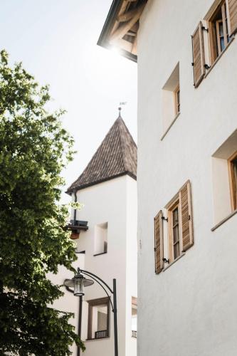 a white building with windows and a street light at Schmitte am Sonnenwirtsplatz Eppan in South Tyrol in Appiano sulla Strada del Vino