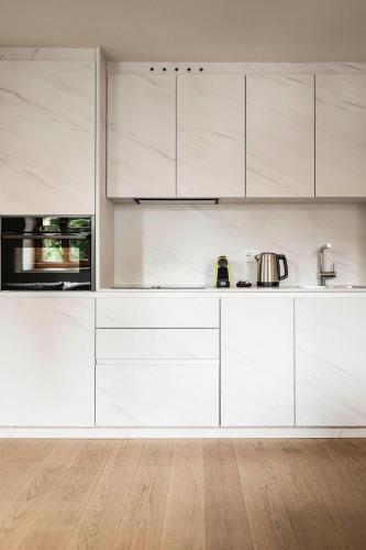 a kitchen with white cabinets and a wooden floor at Schmitte am Sonnenwirtsplatz Eppan in South Tyrol in Appiano sulla Strada del Vino