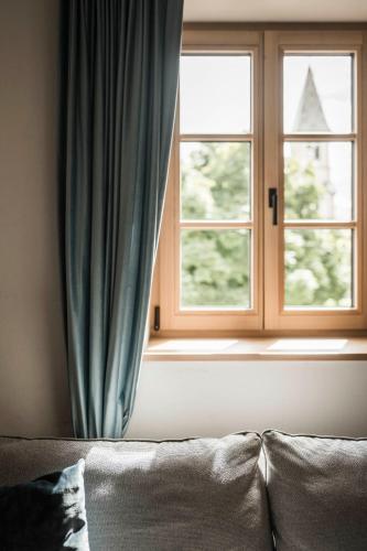 a couch in front of a window with blue curtains at Schmitte am Sonnenwirtsplatz Eppan in South Tyrol in Appiano sulla Strada del Vino