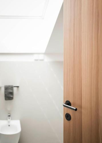 a wooden door in a bathroom with a sink at Schmitte am Sonnenwirtsplatz Eppan in South Tyrol in Appiano sulla Strada del Vino