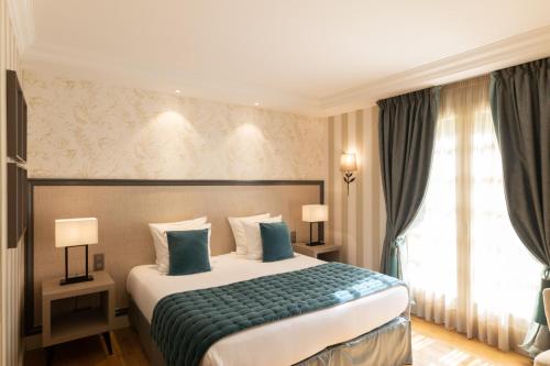 a hotel room with a large bed with blue pillows at Le Château de la Tour in Gouvieux