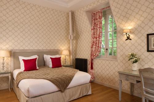 a bedroom with a bed with red pillows and a window at Le Château de la Tour in Gouvieux