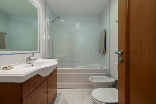 a bathroom with a sink and a tub and a toilet at 1 Bedroom apt with pool access in Albufeira