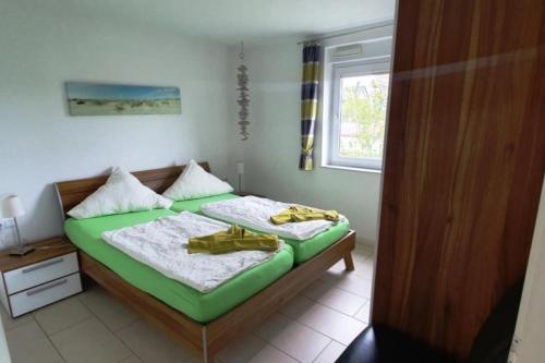 a bedroom with a bed with green sheets and a window at Strandriff in Borkum