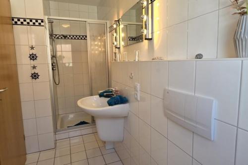 Un baño blanco con lavabo y ducha. en Haus Bremers Hafen, en Borkum