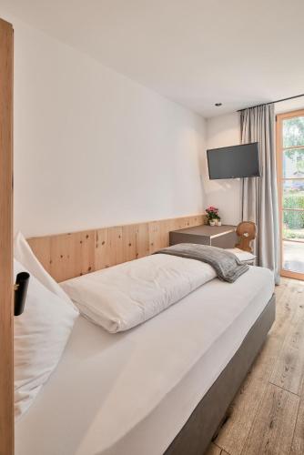 a bedroom with a large white bed and a desk at Hotel Schmuckhof in Chiusa