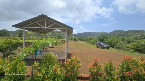 un pavillon avec une voiture garée dans un champ dans l'établissement Potdar holiday home & risort, à Chandoli