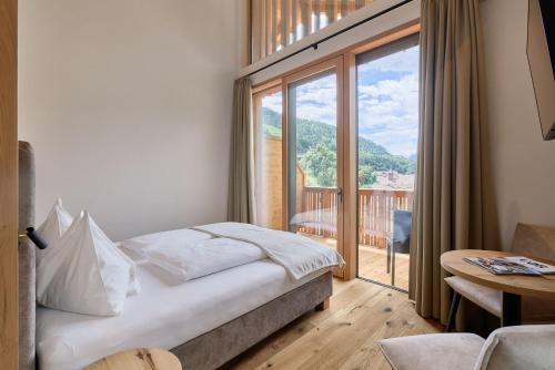 a bedroom with a bed and a large window at Hotel Schmuckhof in Chiusa
