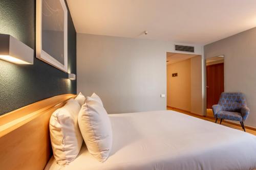 a bedroom with a white bed and a blue chair at Travelodge Murcia in Murcia