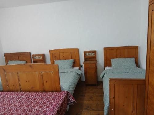 a room with three beds and a table in it at KAMENICA Stara Planina in Dimitrovgrad