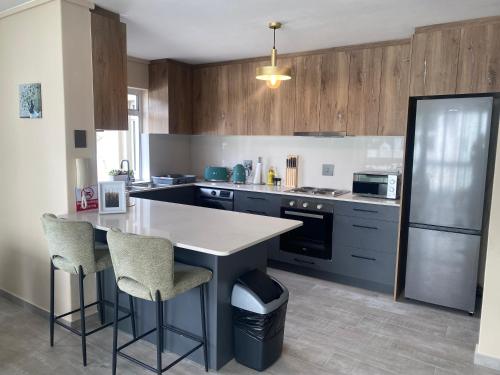 a kitchen with a counter and chairs and a refrigerator at Luxury Holiday Apartment mit 2 Schlafzimmern am Strand von Hout Bay in Hout Bay