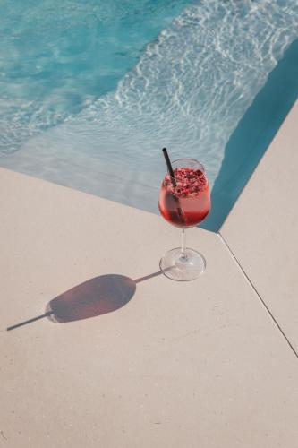 a drink in a glass sitting next to a swimming pool at Residence Traube in Bressanone