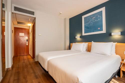 a bedroom with two beds and a blue wall at Travelodge Murcia in Murcia