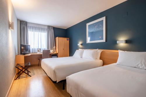 a hotel room with two beds and a desk at Travelodge Murcia in Murcia