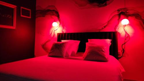 a red bedroom with a bed with red sheets and pillows at La Volupté - Love room avec Jacuzzi - Sauna in Doué-la-Fontaine