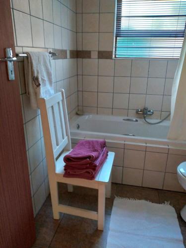 a bathroom with a white tub and a chair with a towel at Bush Beach Safari Accommodation in Jeffreys Bay