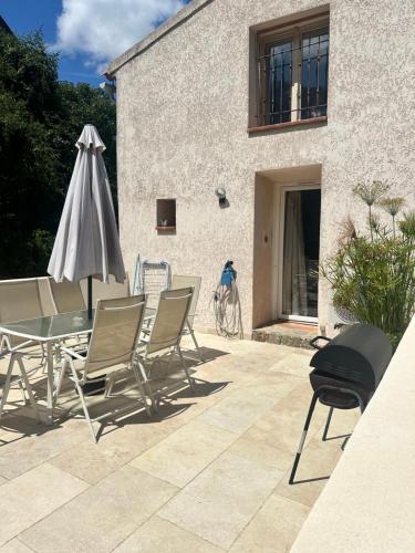 a patio with a table and chairs and an umbrella at L’Attellu in Feliceto