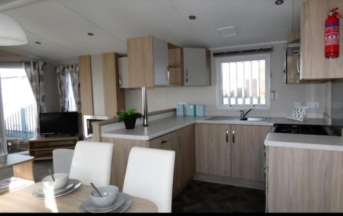 a kitchen with white cabinets and a table and chairs at Lovely Caravan With Free Wi-Fi At Carlton Meres Holiday Park Ref 60034O in Saxmundham
