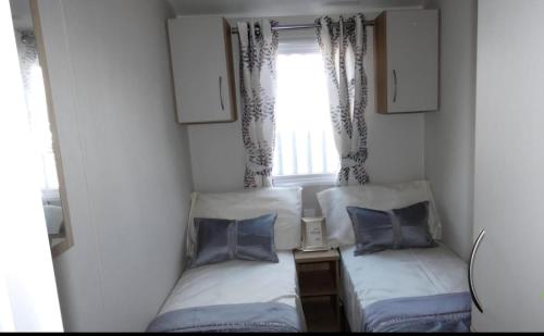 two beds in a small room with a window at Lovely Caravan With Free Wi-Fi At Carlton Meres Holiday Park Ref 60034O in Saxmundham