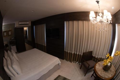 a bedroom with a bed and a table and a chandelier at Hotel Nacional Inn São Carlos & Convenções in São Carlos