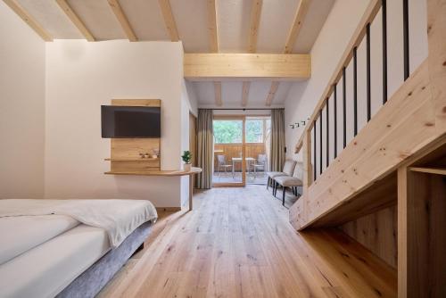 a bedroom with a bed and a staircase with a tv at Hotel Schmuckhof in Chiusa