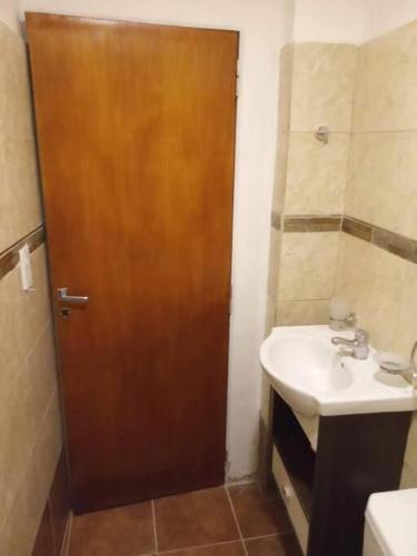 a bathroom with a wooden door and a sink at DEPARTAMENTO 2 DOR ZONA PARQUE CON JACUZZi in Paraná