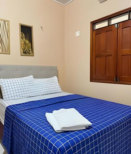 a room with a bed with a blue blanket and a wooden cabinet at Casa Jardim jabuticabas na fronteira in Brasiléia
