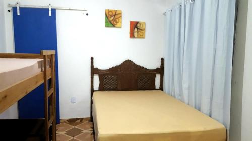 a small bed in a room with a blue wall at Chalé Orquídea Praia de Meaípe - Guarapari, Espírito Santo in Guarapari