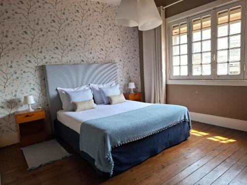 a bedroom with a large bed with a blue blanket at A Casa do Escritor in Vila do Conde