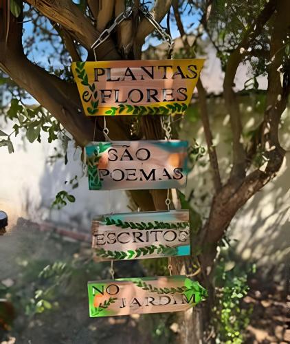 a sign hanging from a tree with plants and flowers at Casa Jardim jabuticabas na fronteira in Brasiléia
