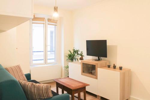 a living room with a tv on a cabinet at bright studio with balcony quiet location in Paris