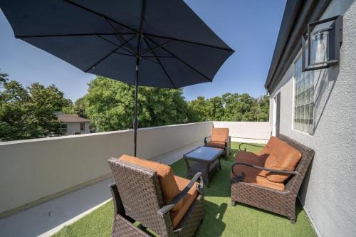 a patio with chairs and an umbrella on a balcony at Best Western Plus Palm Court Hotel in Davis