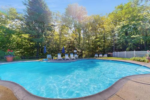 a large swimming pool with chairs in a yard at Slopeside A2 in Stratton