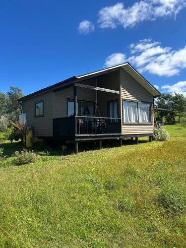 a large house with a porch on a grass field at Maunga Roa Eco Lodge in Hanga Roa