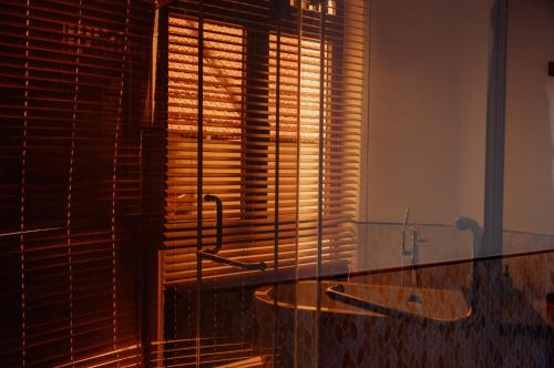 a bathroom with a tub and a window with blinds at Hoian Tranquil Beach Villa in An Bang