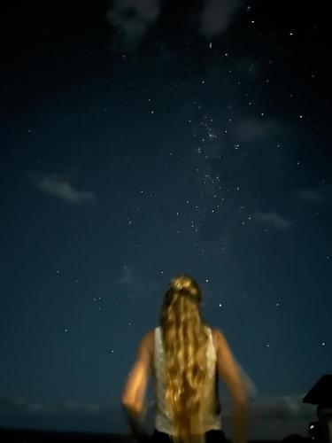 a woman with long blonde hair looking up at the sky at Maunga Roa Eco Lodge in Hanga Roa