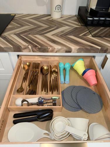a drawer with dishes and utensils on a kitchen counter at Seaberry Hideaway, A Modern 2BR Apt 3miles to Bethany Beach in Ocean View