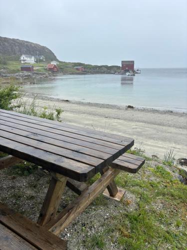 a wooden picnic table sitting on the side of a beach at Fjærestua in Hitra
